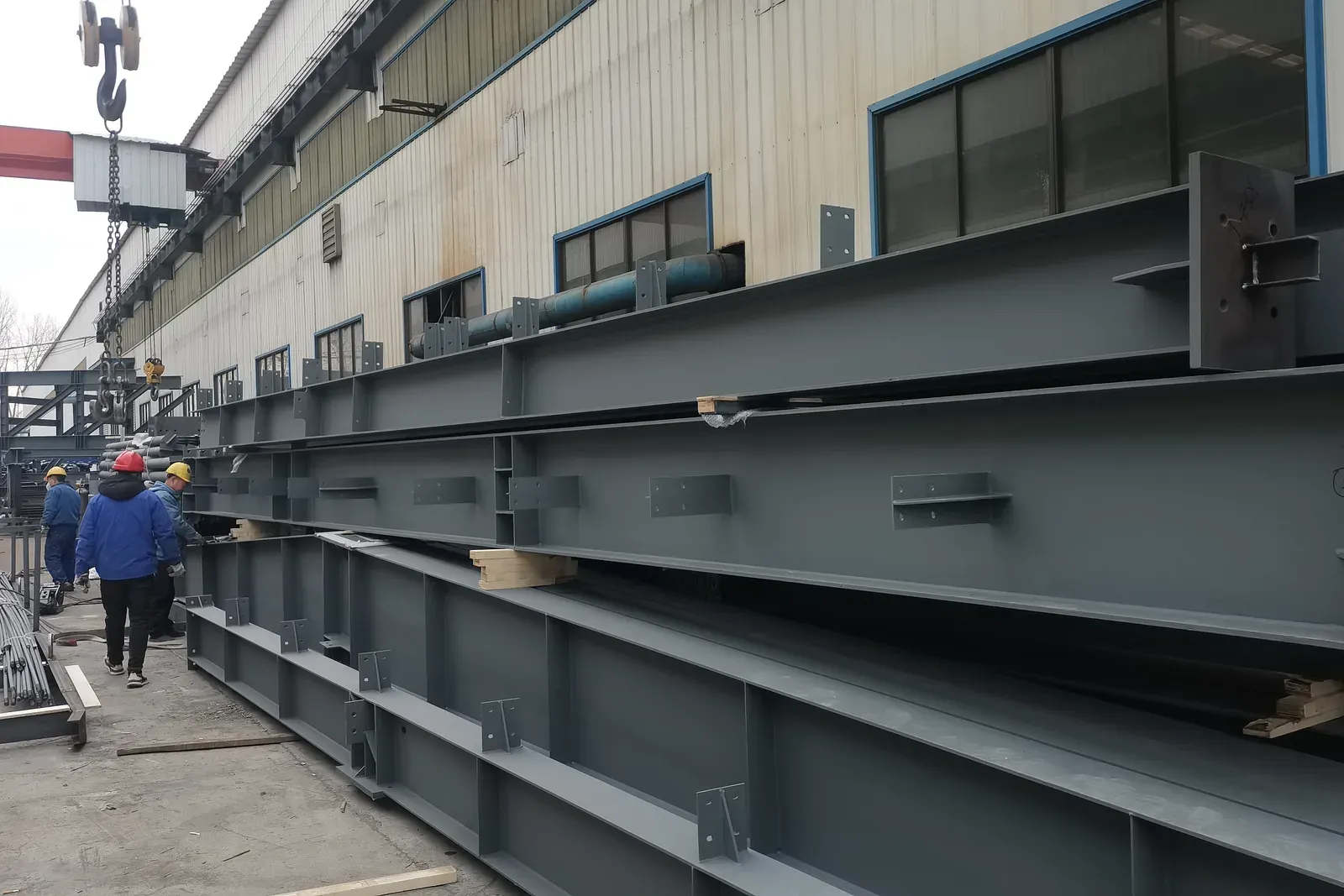 Finished members, staged. Primed girders with fitted connection plates, staged along the bay.