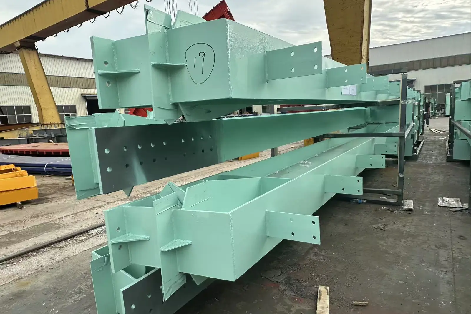 Gantry crane lifting a finished member hand-marked with its package number 19